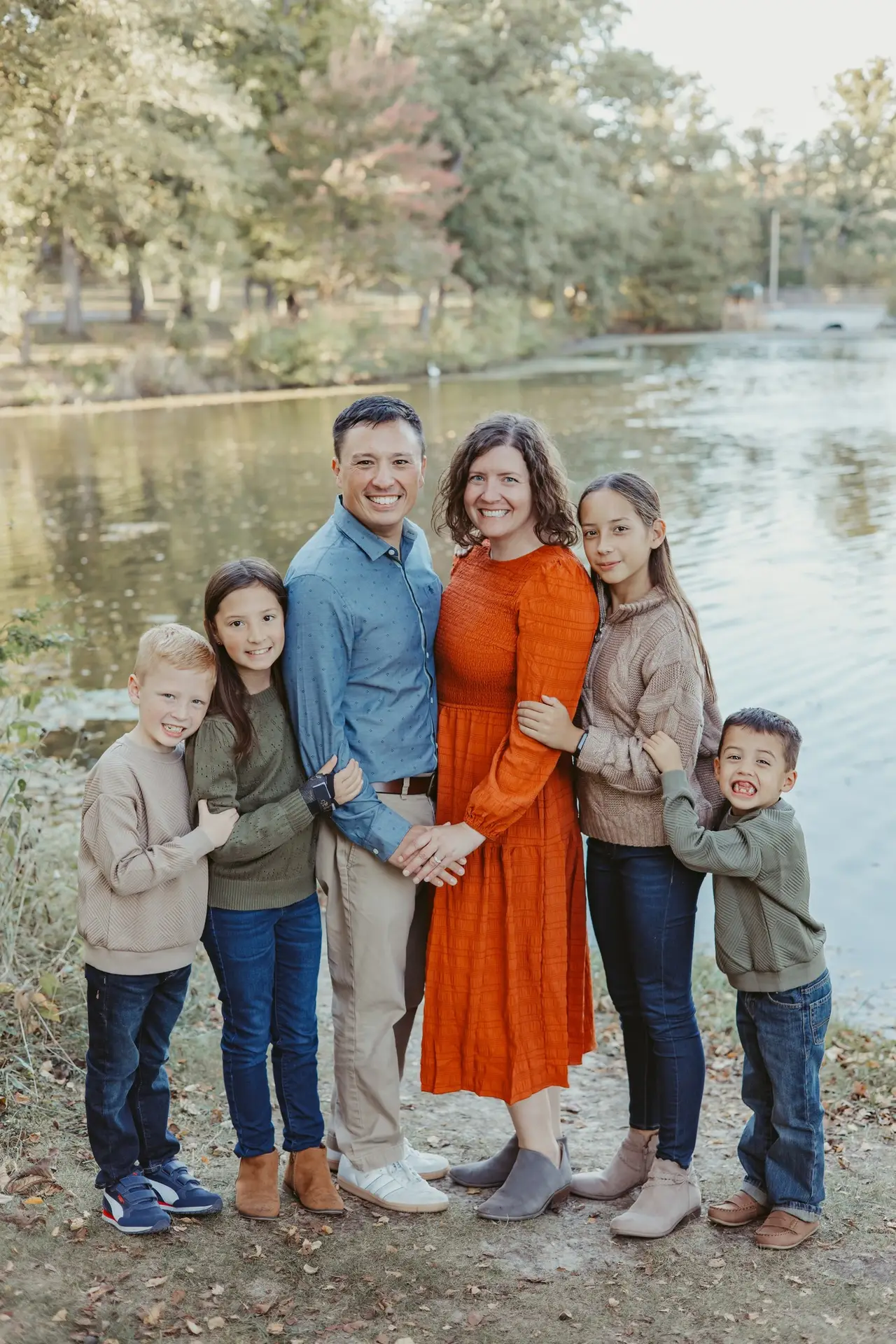 family of six posing for a photo in front of a lake