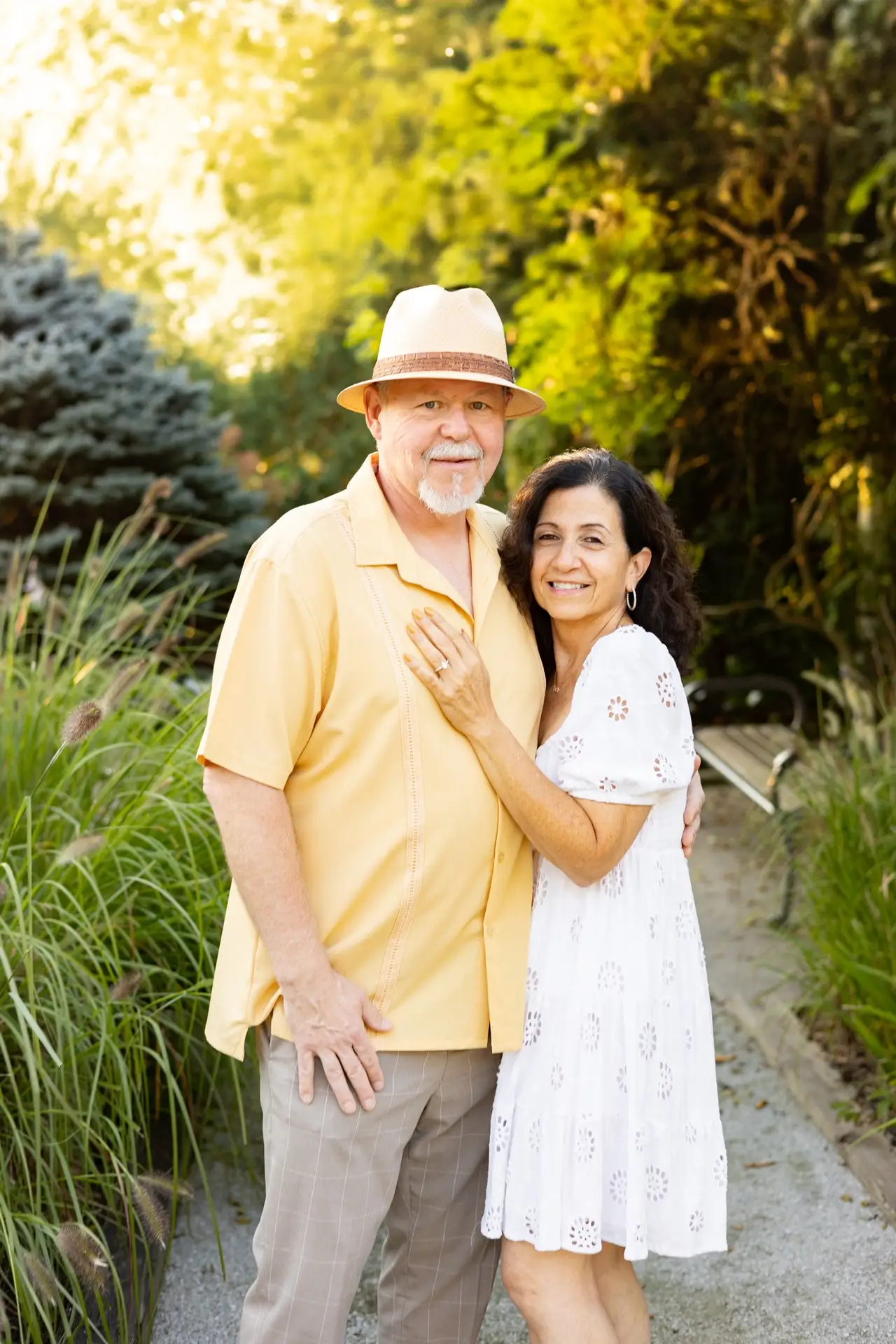 couple posing for a photo in front of trees on a gravel path