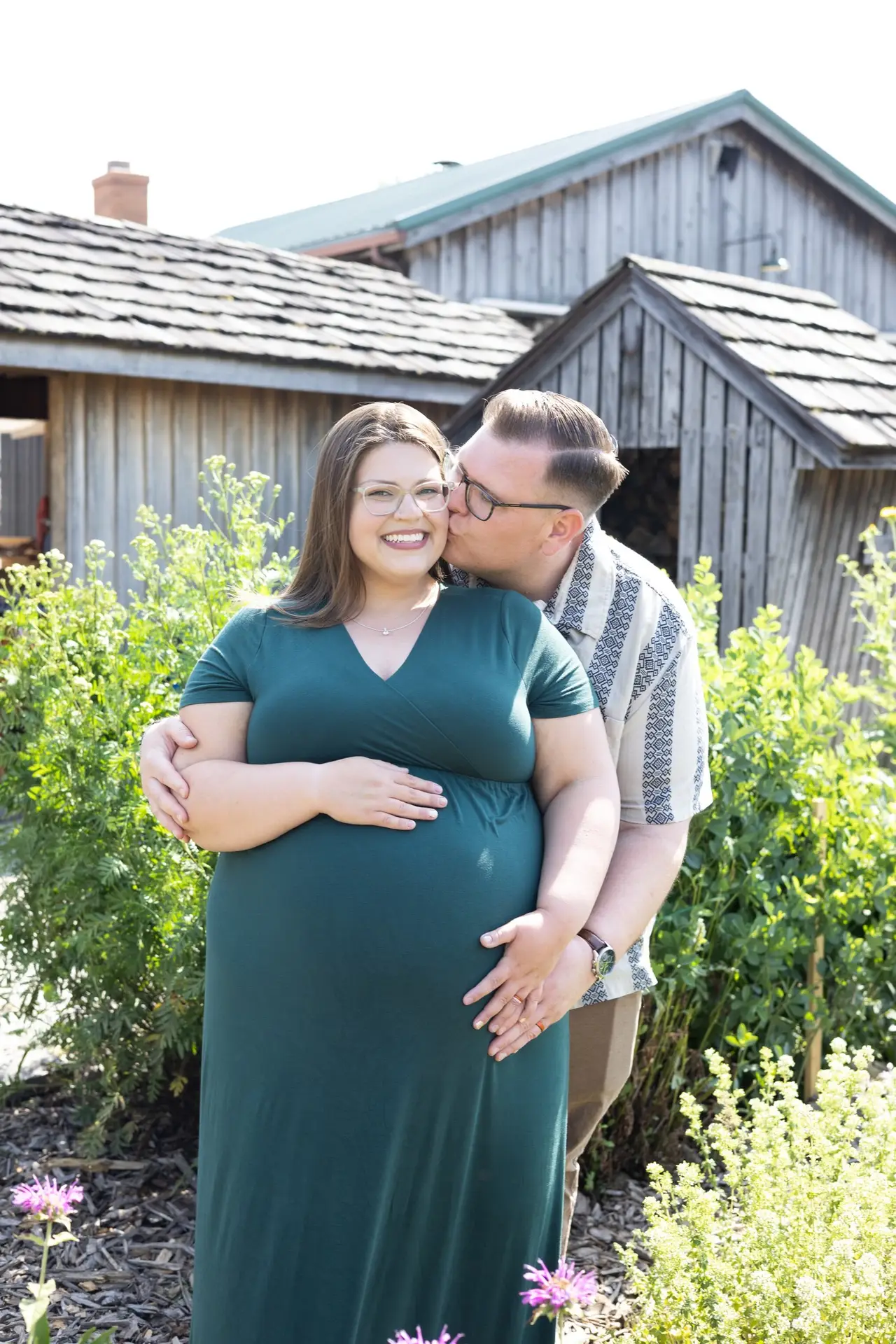Couple kissing in front of a barn
